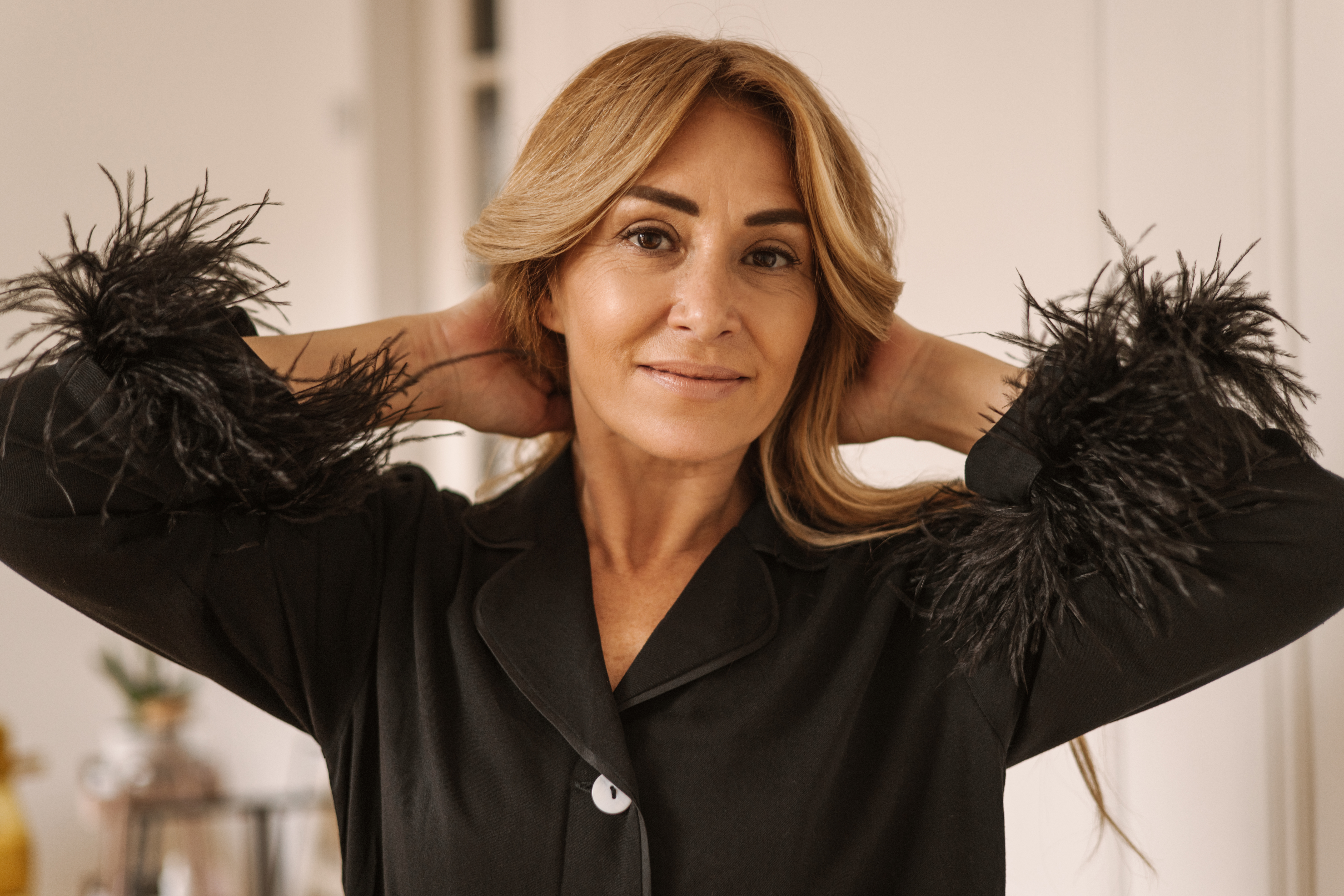 Cute caucasian adult blonde woman in black pajamas looks at camera while being at home. Good morning concept